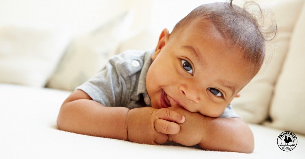 Smiling baby boy lies on his stomach at home