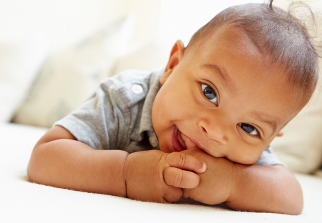 Smiling baby boy lies on his stomach at home