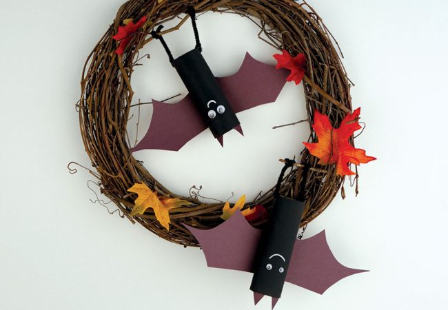 Wreath made from twigs and leaves with recycled toilet roll bats hanging from it