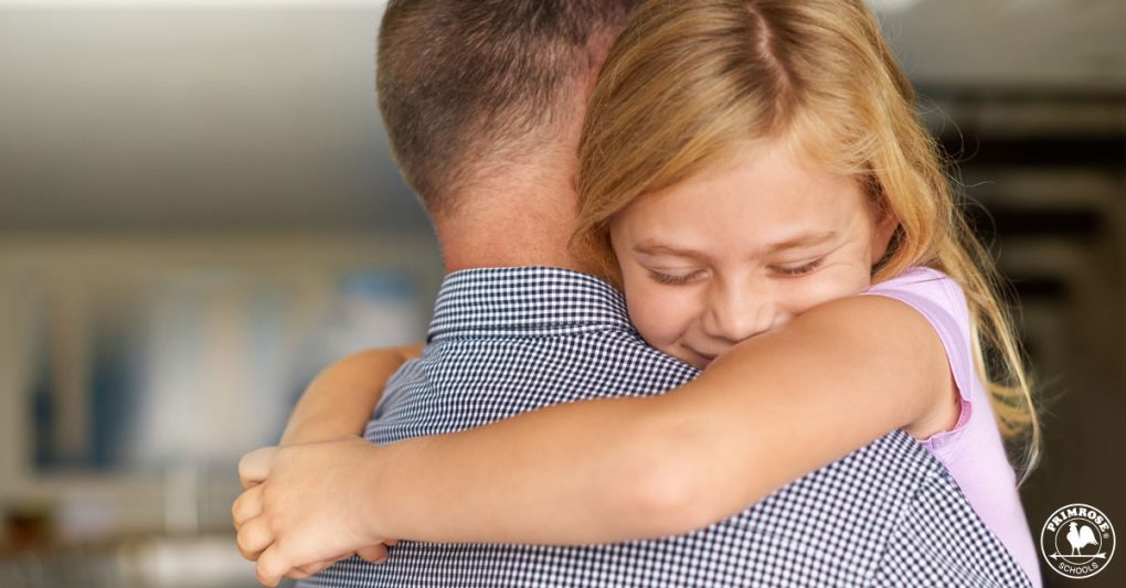 A young happily hugs her father