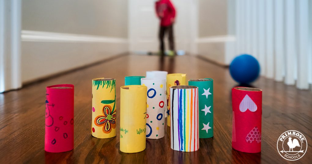 A kid bowling with DIY toilet paper roll pins