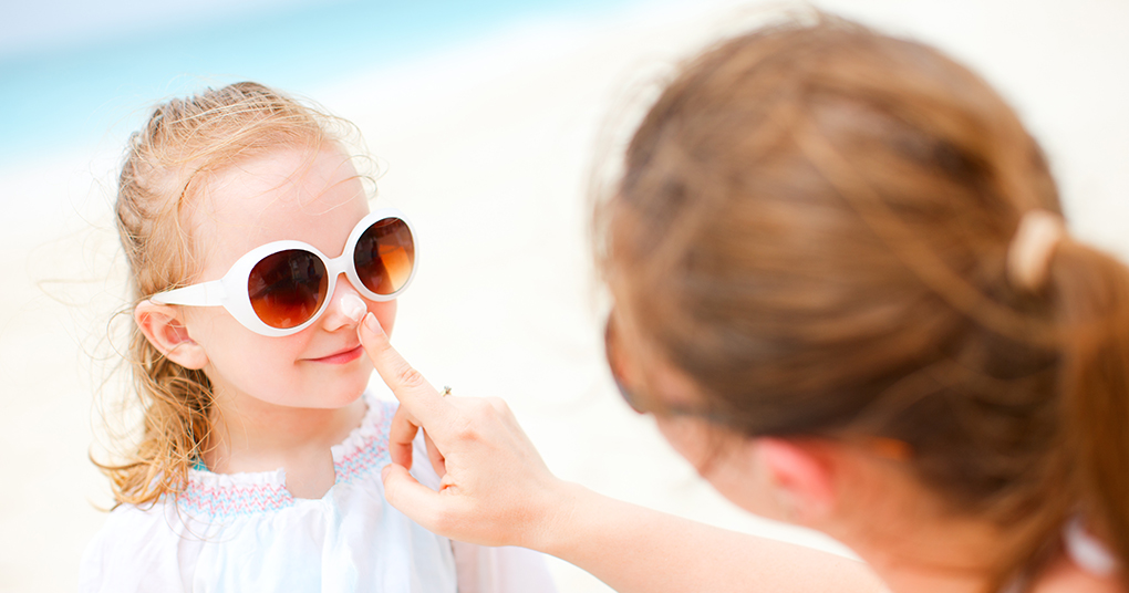 Mother putting sunscreen on a young girl’s nose