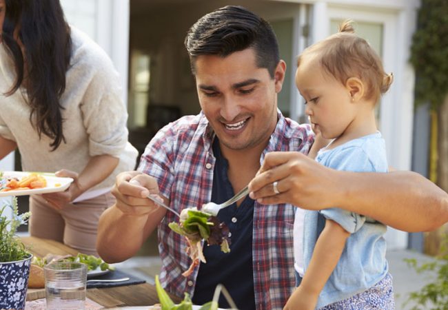 A father serves a family-friendly summer dinner recipe to a young child.