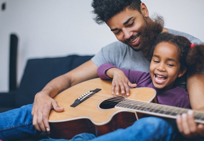 Dad and daughter play music together on guitar