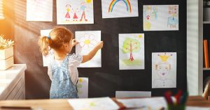 child girl hanging her drawings on the wall