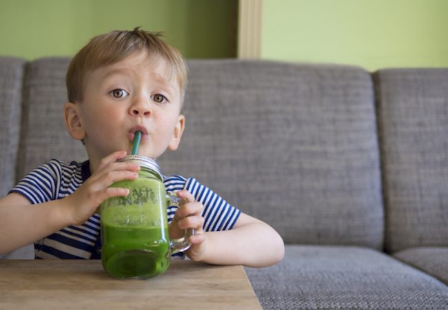 toddler drinking a green smoothie