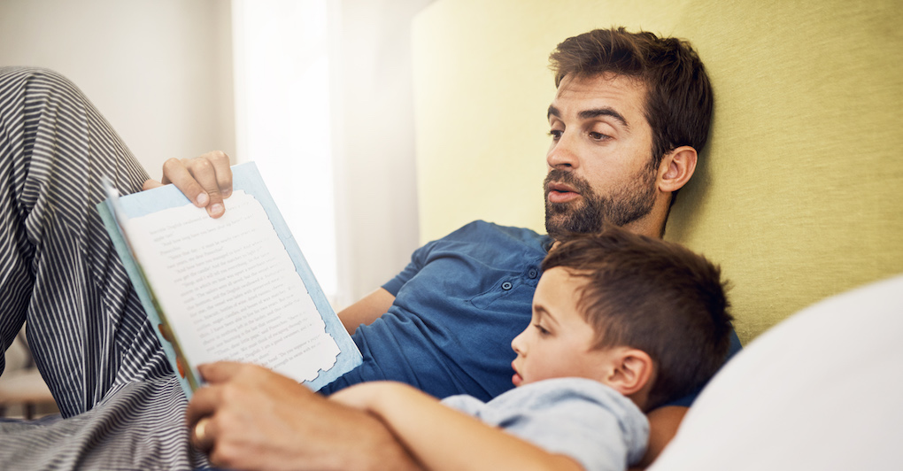 Father reads toddler son a book to help him go to sleep