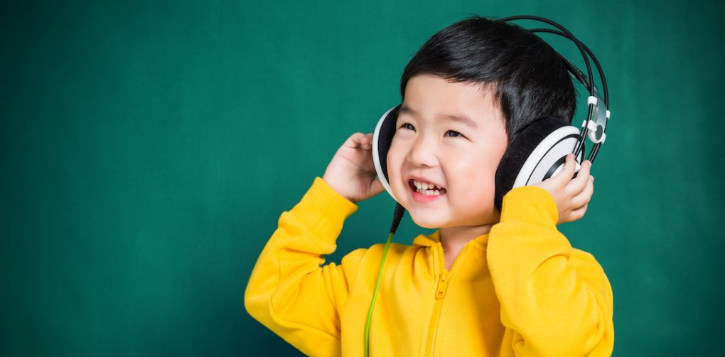 Preschool boy in yellow sweatshirt listens to kid's podcast