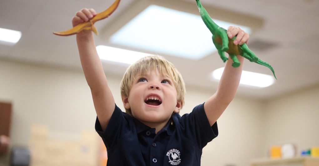 A child within the Primrose classroom playing with two dinosaurs as part of a classroom activity