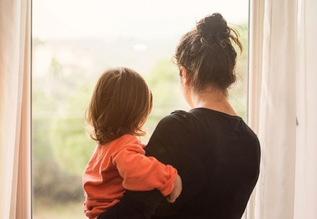 adult woman holding child looking out window