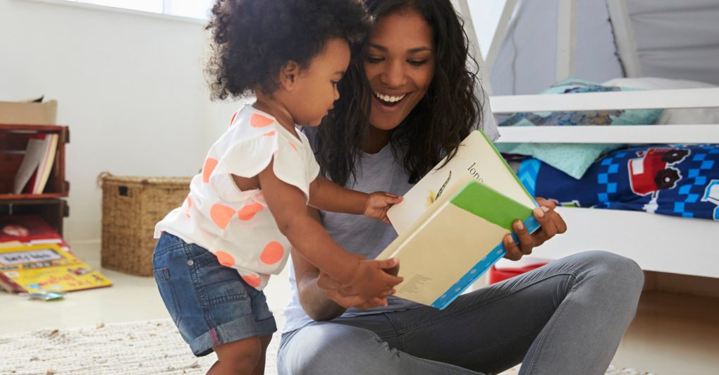 parent and child looking at a book together and smiling
